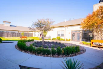 a circular garden with a tree in front of a building